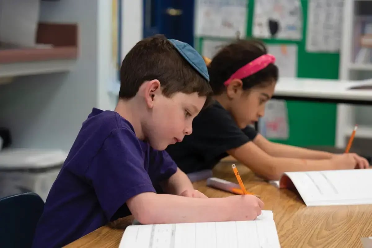 Young students in a Jewish day school classroom in Boston, including a boy wearing a kippah, illustrating the impact of CJP giving.