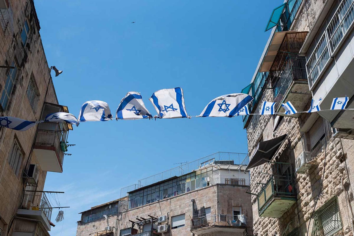 Israeli flags strung across a street between two buildings, symbolizing Jewish community impact in Boston and Jewish philanthropic impact in Boston through global connections.