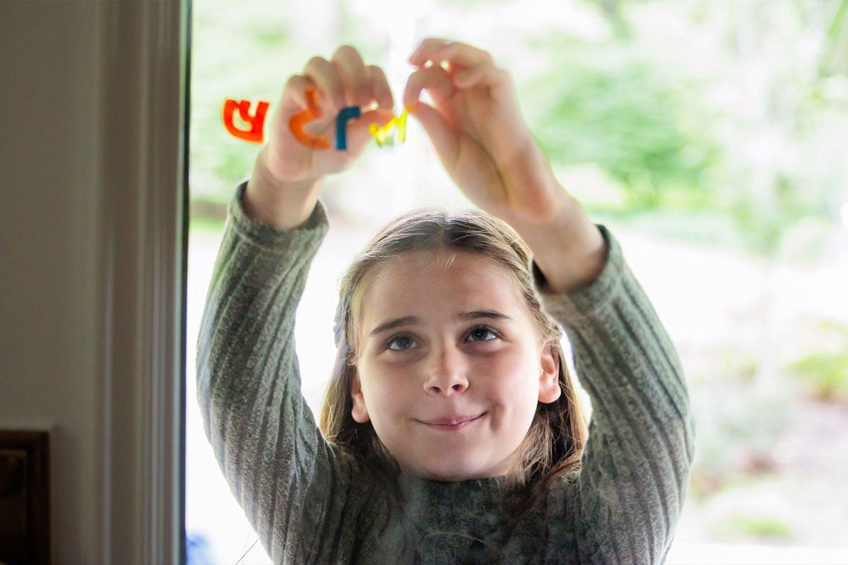Child arranging Hebrew letter stickers, representing Jewish education initiatives supported by Combined Jewish Philanthropies in Boston.
