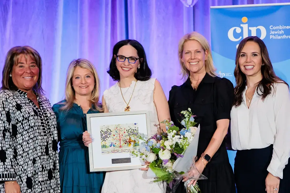 Jewish womens philanthropy: A group of women pose together with flowers and an award during a community leadership and philanthropy recognition event.