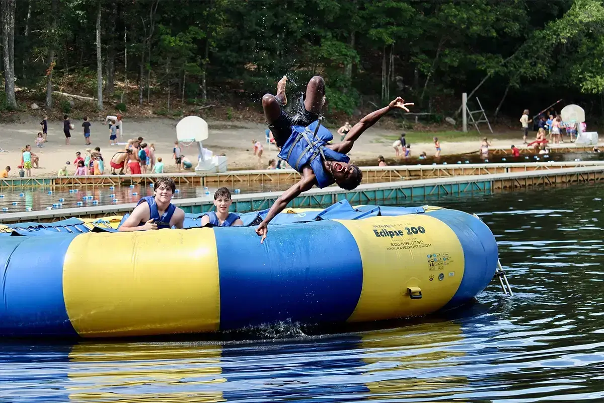 A preteen kid is jumping off a floating raft in a lake with his friends at Jewish summer camp. A preteen kid is jumping off a floating raft in a lake with his friends at Jewish summer camp.